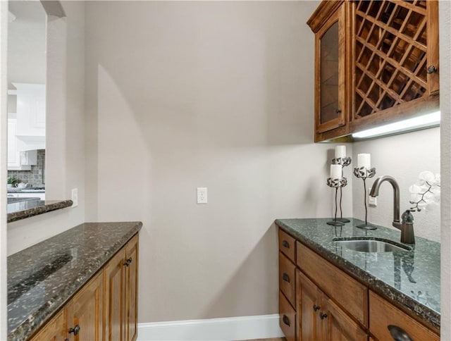 kitchen featuring backsplash, sink, and dark stone counters