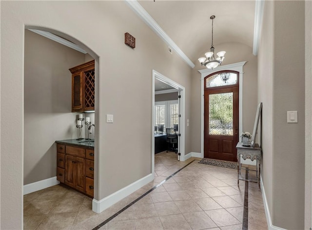 tiled entrance foyer with a chandelier, ornamental molding, sink, and vaulted ceiling