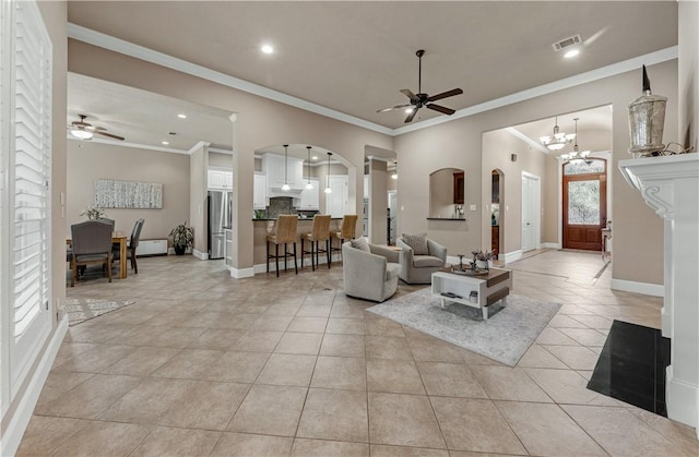 living room with light tile patterned floors, ceiling fan with notable chandelier, and ornamental molding