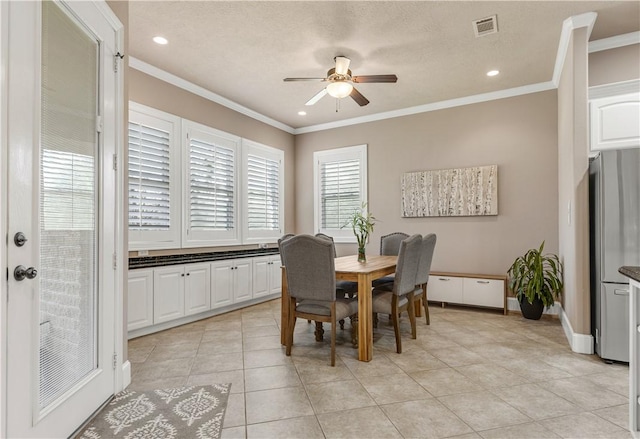 tiled dining area featuring crown molding, ceiling fan, and a textured ceiling