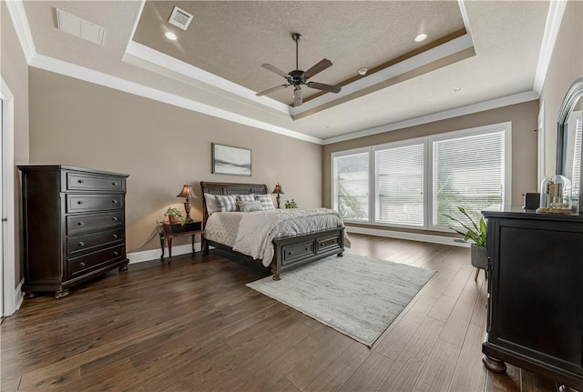 bedroom featuring ceiling fan, dark hardwood / wood-style flooring, crown molding, a textured ceiling, and a tray ceiling