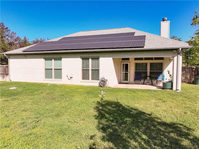 back of property with a yard, a patio, and solar panels