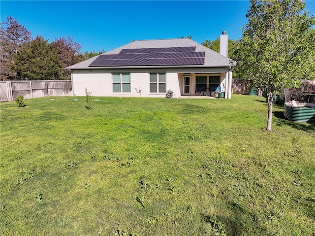 back of house featuring a lawn and solar panels