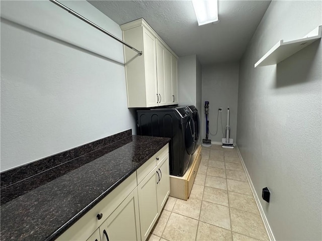 clothes washing area featuring cabinets, separate washer and dryer, a textured ceiling, and light tile patterned floors