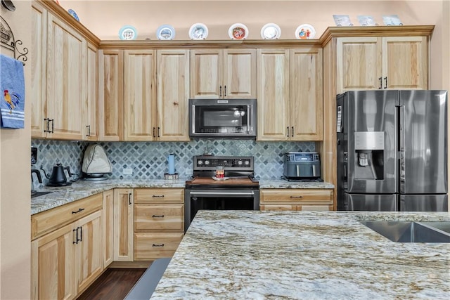 kitchen with light stone counters, appliances with stainless steel finishes, light brown cabinetry, and backsplash