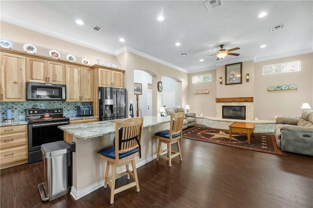 kitchen featuring an island with sink, dark hardwood / wood-style flooring, a kitchen bar, black appliances, and light stone countertops