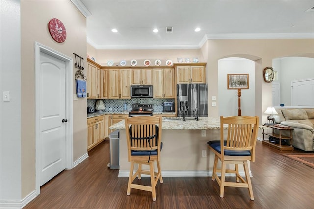 kitchen featuring a breakfast bar area, a center island, tasteful backsplash, light stone countertops, and black appliances