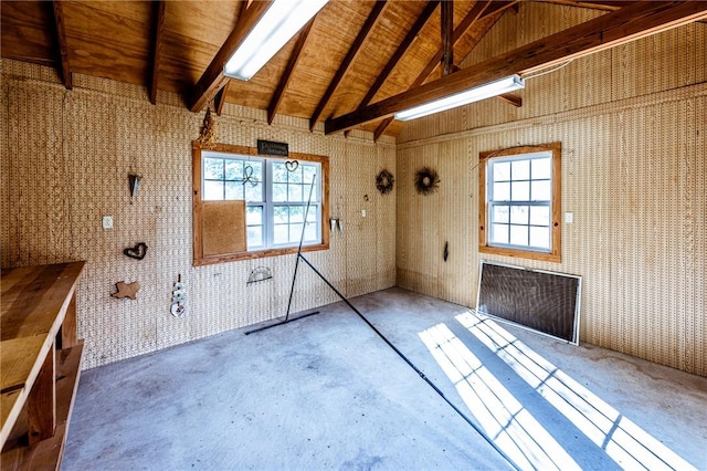 interior space with plenty of natural light, concrete floors, beam ceiling, and wood walls