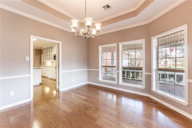 empty room with plenty of natural light, a tray ceiling, crown molding, and an inviting chandelier