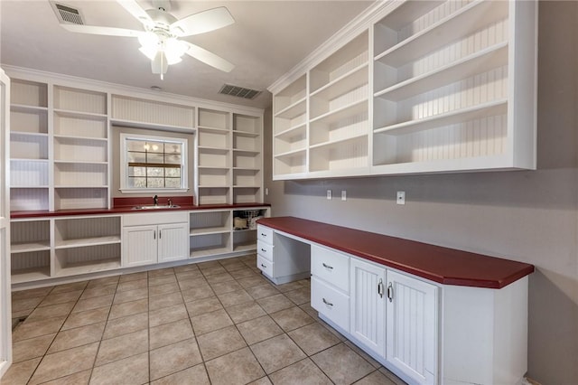 kitchen featuring built in desk, light tile patterned floors, ceiling fan, and white cabinetry