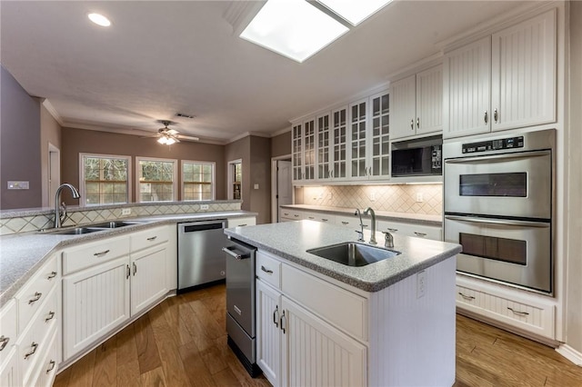 kitchen with sink, backsplash, appliances with stainless steel finishes, and a kitchen island with sink