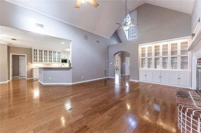 unfurnished living room featuring ceiling fan, a towering ceiling, and hardwood / wood-style floors