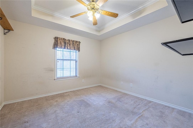 carpeted spare room featuring a tray ceiling, ceiling fan, and crown molding