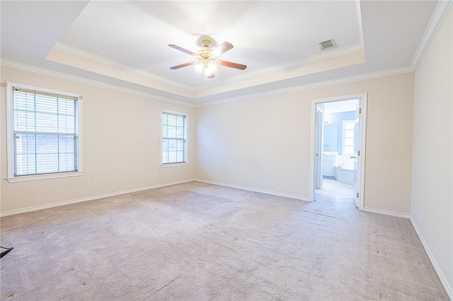 unfurnished room with light carpet, crown molding, a tray ceiling, and ceiling fan