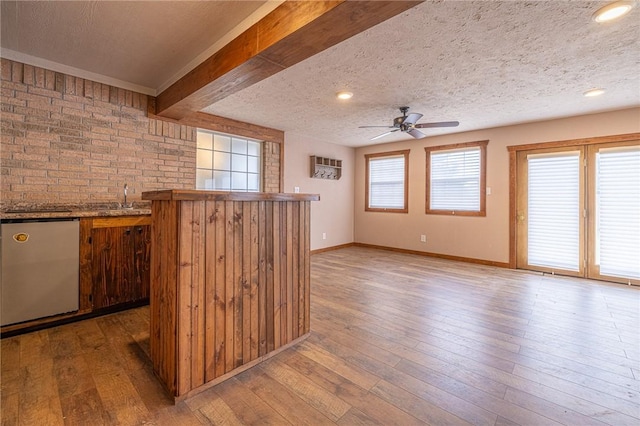 kitchen with hardwood / wood-style flooring, dishwashing machine, ceiling fan, a textured ceiling, and beamed ceiling