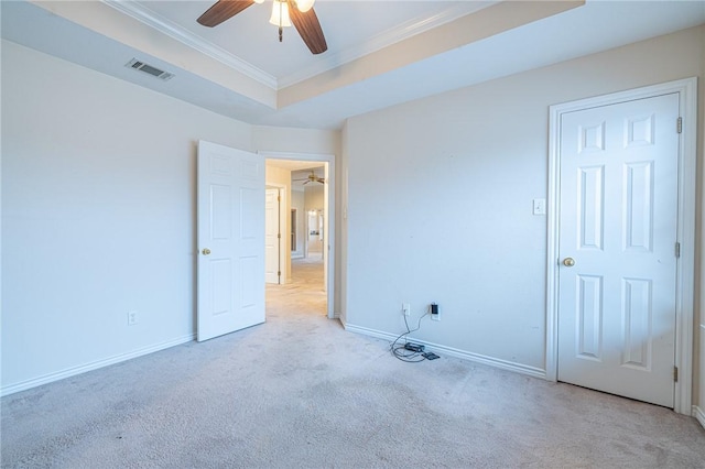 carpeted empty room featuring ceiling fan, ornamental molding, and a raised ceiling