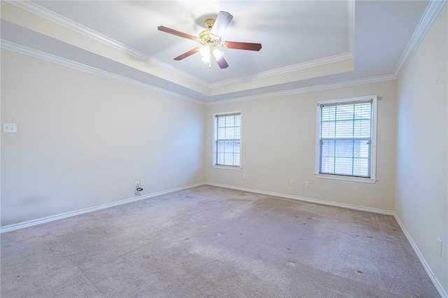 empty room featuring a raised ceiling, ceiling fan, crown molding, and light colored carpet