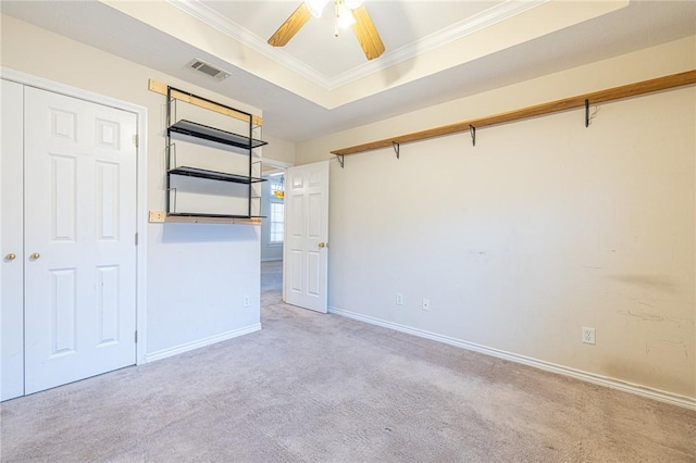 carpeted empty room with a tray ceiling, ceiling fan, and crown molding