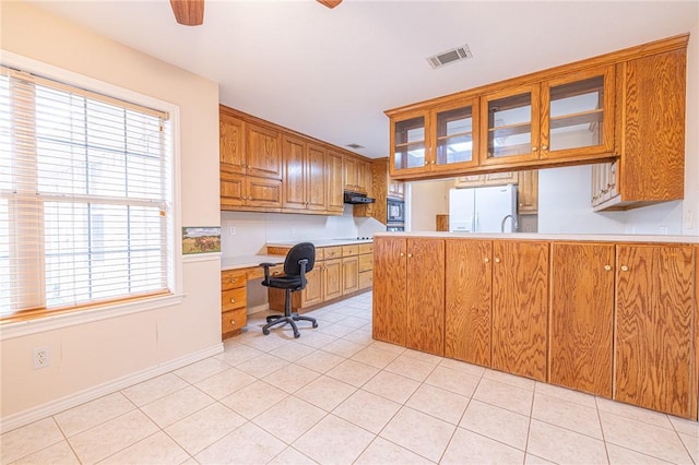 unfurnished office with light tile patterned flooring, ceiling fan, and built in desk