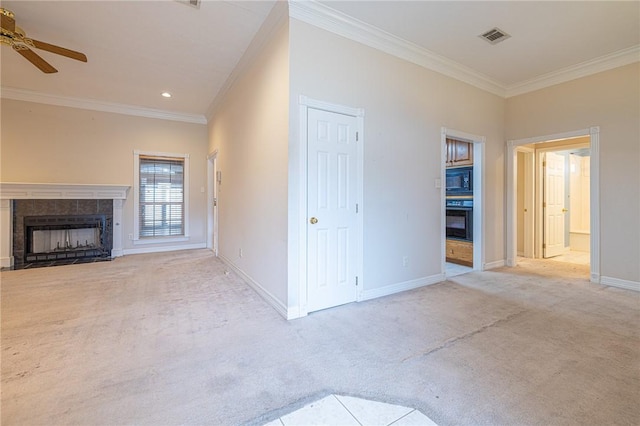 unfurnished living room featuring a tile fireplace, ceiling fan, light colored carpet, and ornamental molding