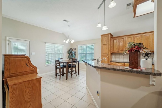 kitchen featuring decorative light fixtures, light tile patterned floors, a chandelier, and vaulted ceiling