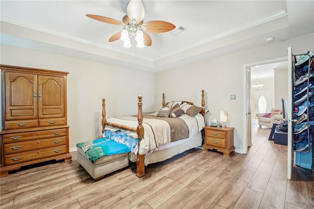 bedroom featuring ceiling fan, ornamental molding, light hardwood / wood-style flooring, and a tray ceiling