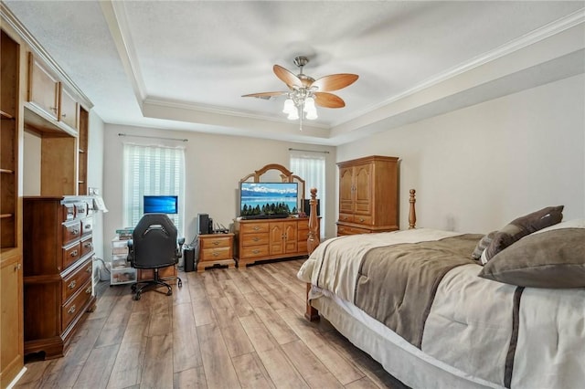 bedroom with a tray ceiling, ceiling fan, light hardwood / wood-style flooring, and crown molding