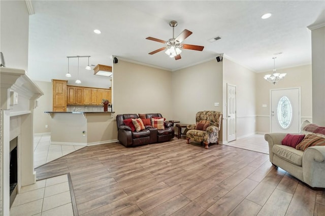 living room with light wood-type flooring, ceiling fan with notable chandelier, and crown molding