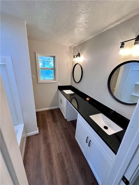 bathroom with hardwood / wood-style floors, vanity, and a textured ceiling