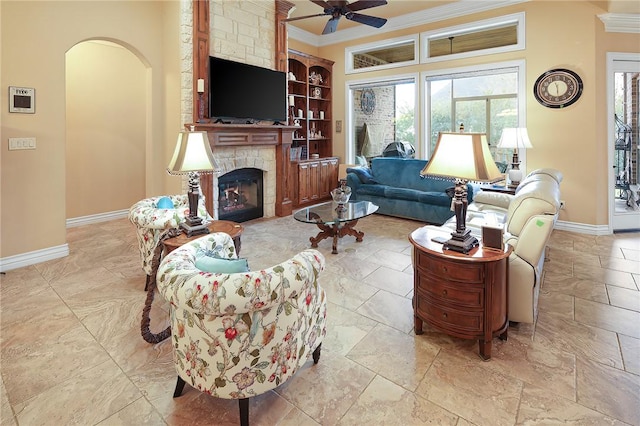 living room featuring ornamental molding, ceiling fan, a fireplace, and built in shelves