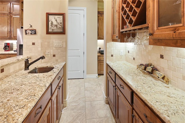 kitchen with sink, decorative backsplash, and light stone countertops