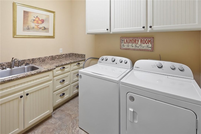 clothes washing area with sink, washing machine and dryer, and cabinets