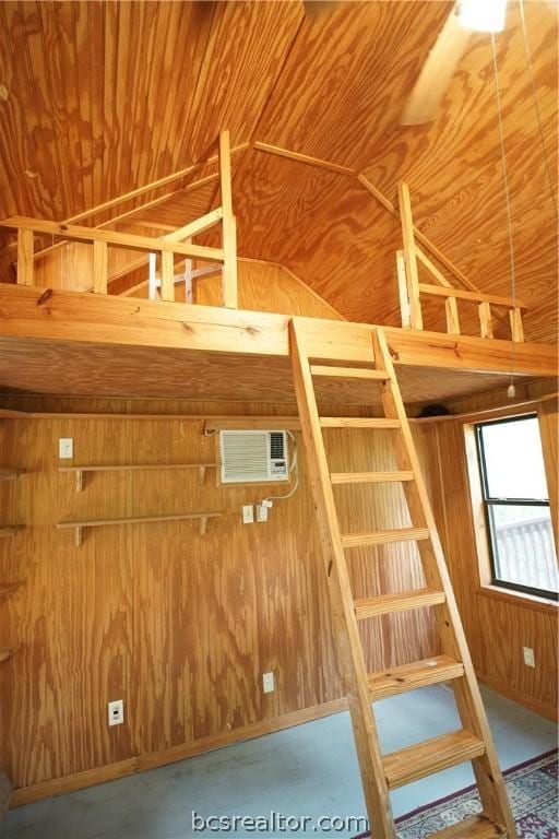 interior space featuring lofted ceiling, wooden walls, concrete flooring, and a wall mounted air conditioner