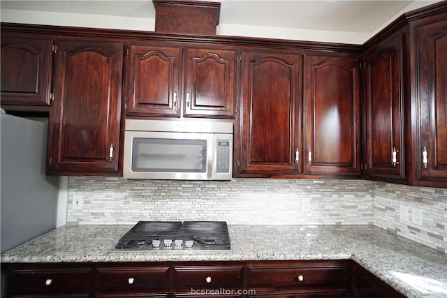 kitchen with decorative backsplash, stainless steel appliances, and light stone countertops