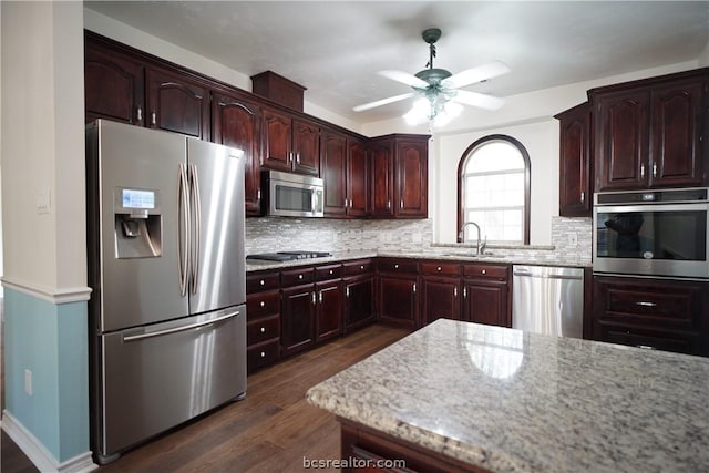 kitchen with appliances with stainless steel finishes, tasteful backsplash, ceiling fan, sink, and dark hardwood / wood-style floors