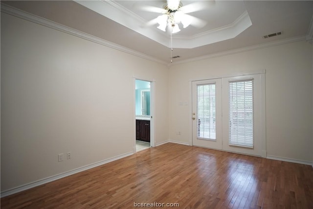 spare room with a tray ceiling, crown molding, hardwood / wood-style floors, and ceiling fan