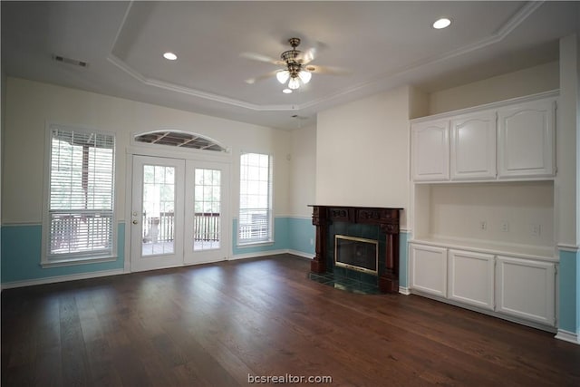 unfurnished living room with a raised ceiling, ceiling fan, a fireplace, and dark wood-type flooring