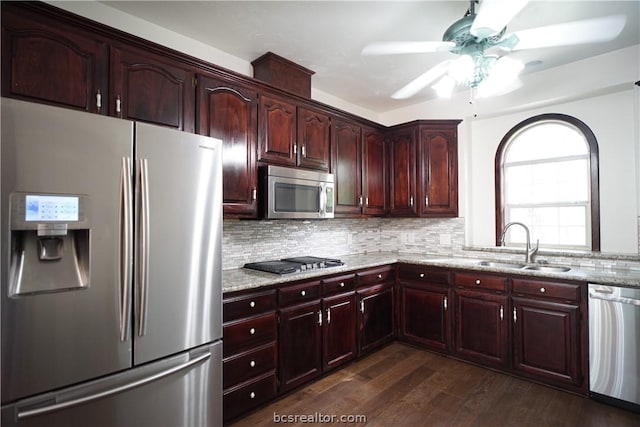 kitchen featuring sink, dark wood-type flooring, light stone counters, backsplash, and appliances with stainless steel finishes