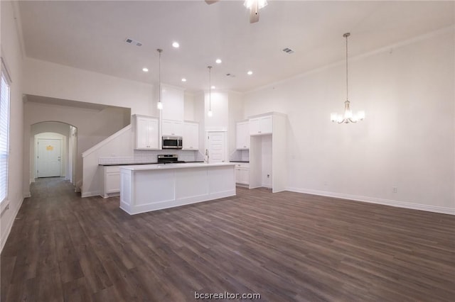 kitchen featuring white cabinetry, stainless steel appliances, dark hardwood / wood-style floors, decorative light fixtures, and a kitchen island with sink