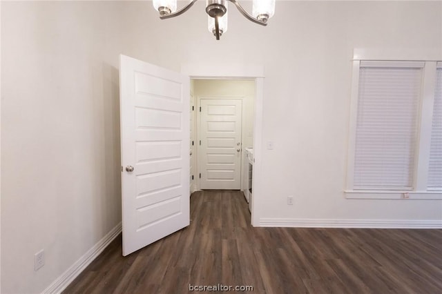 spare room with a notable chandelier and dark hardwood / wood-style flooring