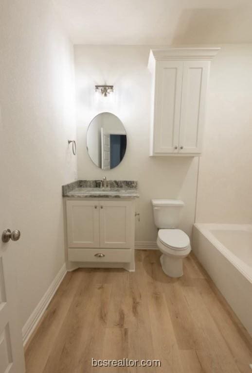 bathroom featuring hardwood / wood-style floors, vanity, toilet, and a bathing tub