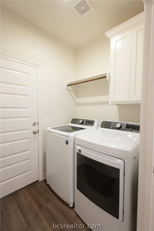 laundry area featuring cabinets, separate washer and dryer, and dark wood-type flooring