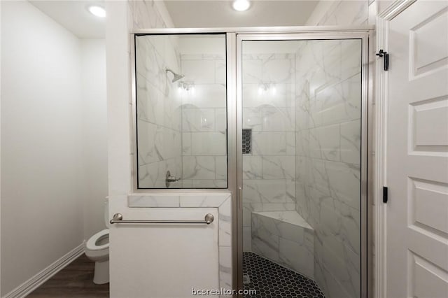 bathroom with hardwood / wood-style floors, an enclosed shower, and toilet