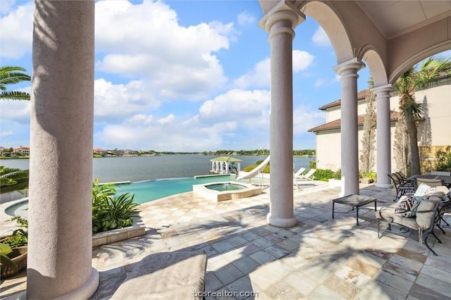 view of pool with an in ground hot tub, a water view, and a patio area