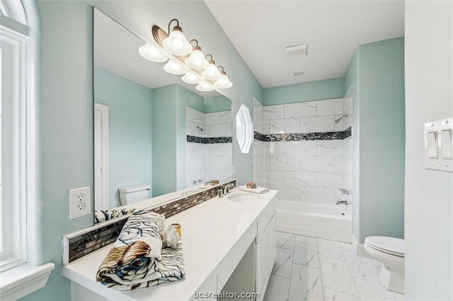 full bathroom featuring vanity, tiled shower / bath combo, and toilet