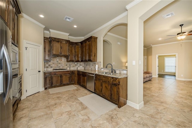 kitchen with sink, tasteful backsplash, crown molding, appliances with stainless steel finishes, and light stone countertops