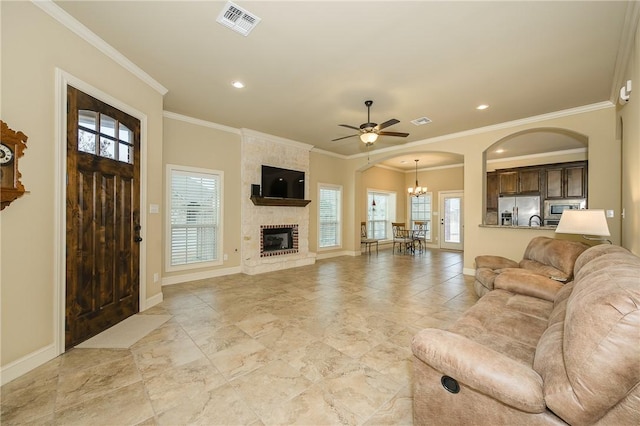 living room with crown molding, ceiling fan with notable chandelier, and a fireplace