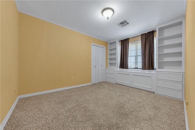 spare room with carpet flooring, built in features, and crown molding