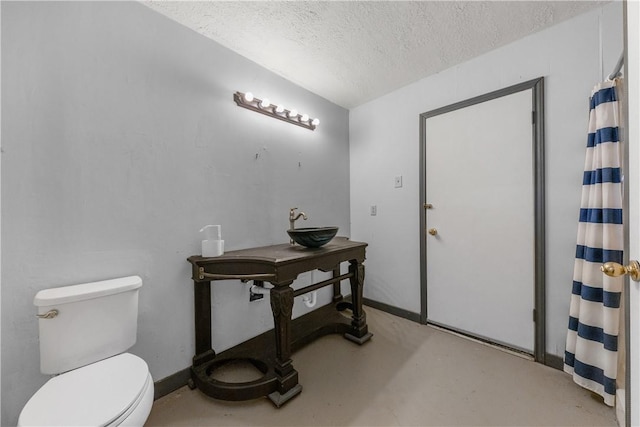 bathroom featuring sink, concrete floors, a textured ceiling, and toilet