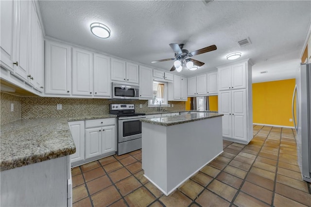 kitchen featuring a center island, stainless steel appliances, white cabinetry, and backsplash